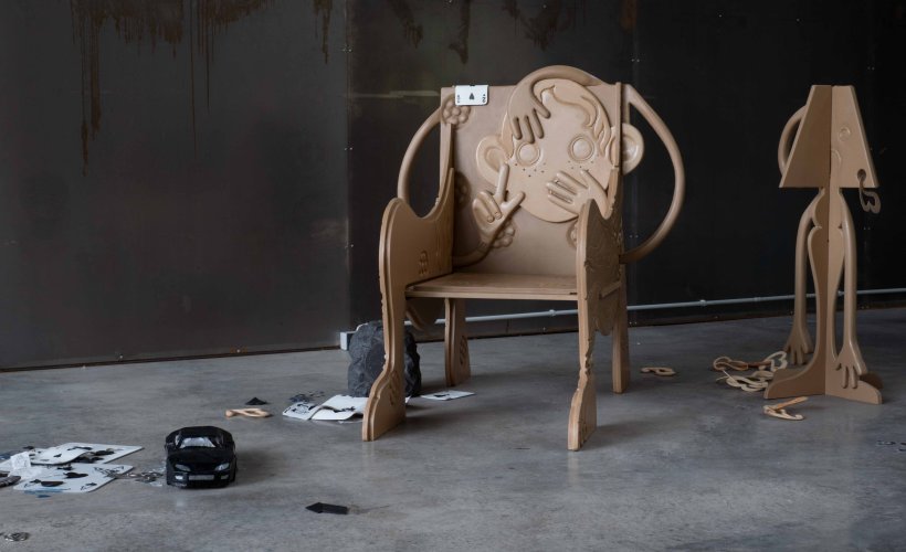 Installation eines geschnitzten Stuhls, Lampe, Spielzeugauto, Papier, und Trümmer