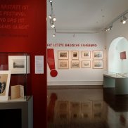 Blick in den Ausstellungsraum mit Vitrinen und Grafiken an den Wänden