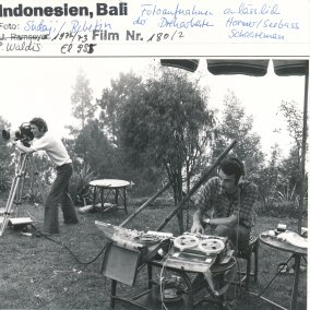  Fotoaufnahme anlässlich der Dreharbeiten in Bali (1972), mit Mann mit Kamera auf Stativ (stehend) und Mann an Aufnahmegerät (sitzend)