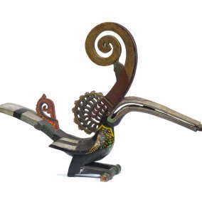 Vogelfigur in Gold- und Rottönen mit sehr langem Schnabel und langem, geschwungenen Horn.