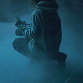 Ein Foto einer Frau, die von hinten her fotografiert wird, sie sitzt im Nebel